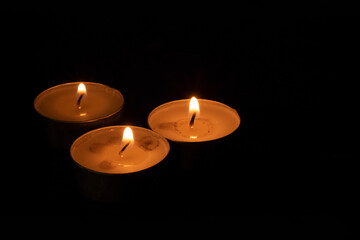 The candle flame is approaching the dark background in the night.	