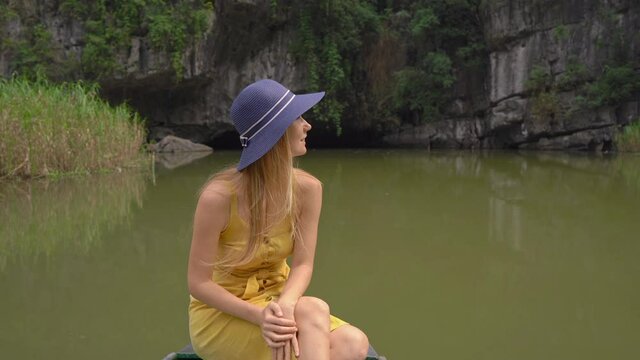 A young woman on a boat having a river trip among rocks in Ninh Binh, a tourist destination in northern Vietnam. Travel to Vietnam concept