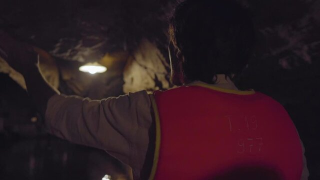 Closeup shot of a young man in a boat that moves through a cave carved through a mountain in limestone rocks area in Ninh Binh, a tourist destination in northern Vietnam. Travel to Vietnam concept