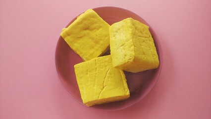 Yellow tofu made from soybeans, a traditional Indonesian food with a pink plate background