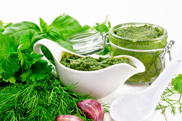 Sauce of spicy greens in gravy boat and jar on light board