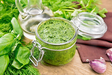 Sauce of spicy greens in jar on wooden board