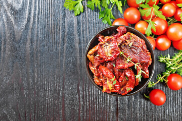 Tomatoes sun-dried in bowl on board top