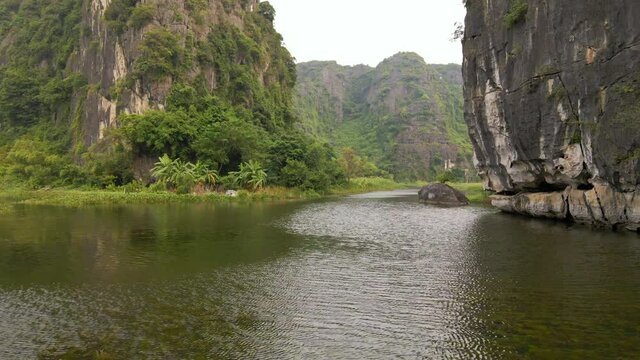 Aerial shot of beautiful limestone mountains with passes carved by a river in Ninh Binh region, a famous tourist destination in northern Vietnam. Travel to Vietnam concept