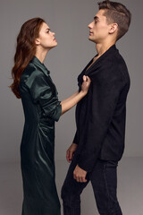 A woman looks indignantly at a young man in a suit on a gray background