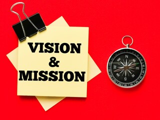 Text VISION AND MISSION on paper notes with compass isolated on red background.