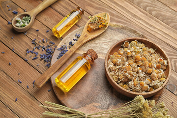Composition with herbs and bottles of essential oil on wooden background