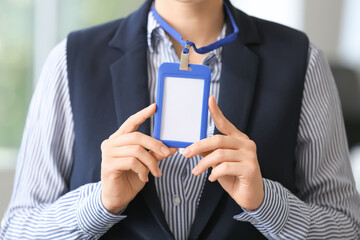 Young woman with blank badge in office, closeup