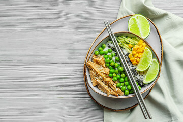 Bowl with tasty rice, chicken and vegetables on wooden background