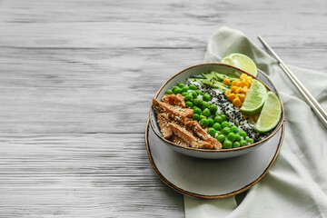 Bowl with tasty rice, chicken and vegetables on wooden background
