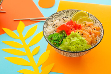 Bowl with tasty rice, fish and vegetables on color background