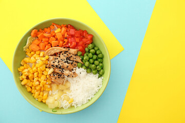 Bowl with tasty rice, chicken and vegetables on color background