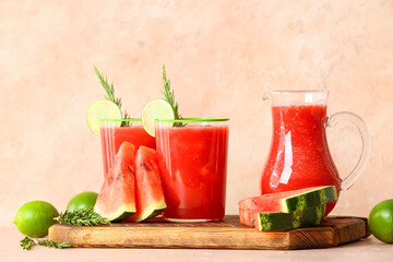 Glasses with fresh watermelon juice and lime on color background
