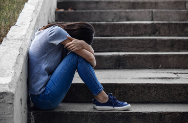 Depressed young woman sitting on stairs outdoors