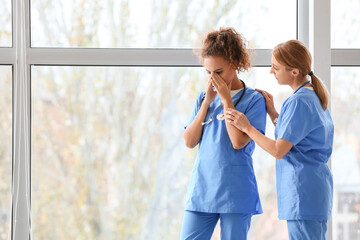 Female doctor calming her colleague in clinic
