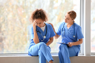 Female doctor calming her colleague in clinic