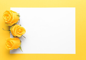 Composition with beautiful yellow roses and blank paper on color background