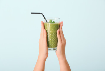 Hands with healthy vegetable smoothie on color background
