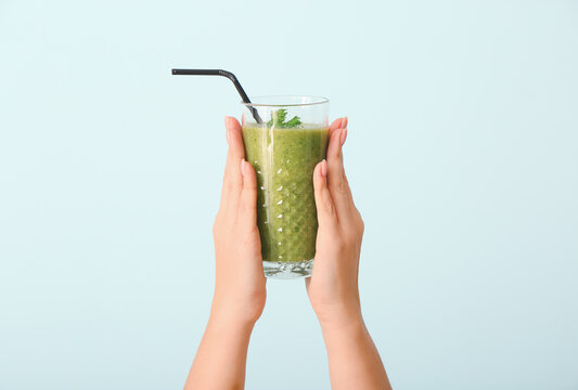 Hands with healthy vegetable smoothie on color background