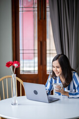 beutiful woman working on laptop in the room while hold a cup of  coffee.