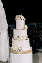wedding cake white three tiers on a dark background with white and yellow roses with gold edging