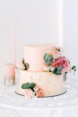 delicate beige wedding cake decorated with delicate pink yellow roses and eucalyptus on a light background