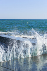 The sea wave breaks on the pier into a lot of splashes