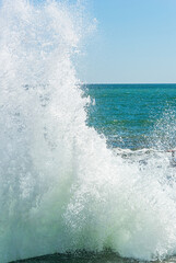 Fototapeta premium A huge sea wave breaks into splashes on the pier. Vertical photo