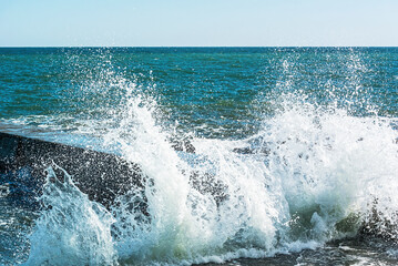 The sea wave breaks into splashes on the pier. Close-up photo