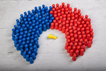 blue and red wooden figurines surrounding a fallen yellow figurine, symbol for failed leader