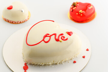 A cake in heart shape. Mousse cake in the shape of a heart with the inscription love with cupcakes  on a gray background. Valentine's Day.