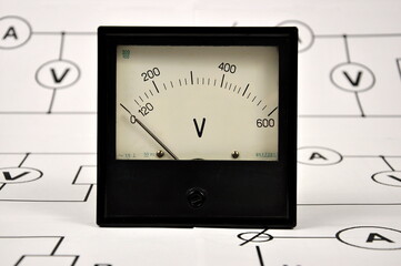 Basic electrical diagram and a black old voltmeter.
