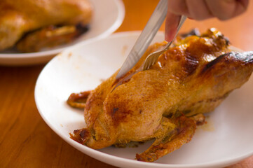Duck baked in the oven, stuffed with apples. The chef carves the duck on a platter.