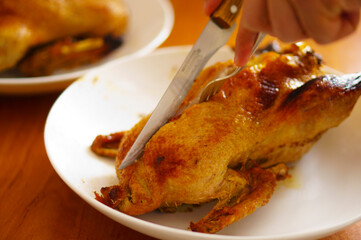 Duck baked in the oven, stuffed with apples. The chef carves the duck on a platter.