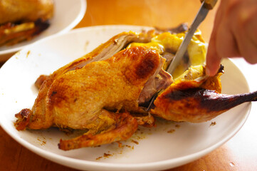 Duck baked in the oven, stuffed with apples. The chef carves the duck on a platter.