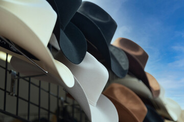 An isolated point of view of an outdoor retail display of different colored cowboy hats under a...
