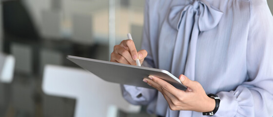 Close up view of businesswoman hand holding stylus pen writing on screen of digital tablet while...