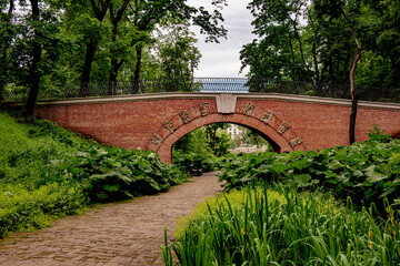 stone brick vintage bridge in the park on a summer day in the grass