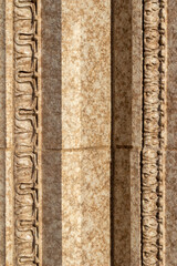 Close up abstract texture background of a beautiful exterior beige color vintage marble stone wall, with intricate moulding contrasting with clean geometric block shape stones