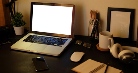 Mock up laptop computer with blank screen, coffee cup and notebook on modern workspace.