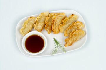 Top view of Gyoza served on a long white plate and ready with soy sauce. Isolated white background.
