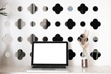 Mock up laptop computer with blank screen, coffee cup and notebook on modern workspace.