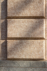 Close up abstract texture background of a beautiful exterior beige color vintage marble stone wall, with intricate moulding contrasting with clean geometric block shape stones