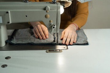 A young girl is sitting at a sewing machine in the workshop. Sewing dresses according to the author's pattern. Sewing atelier concept.