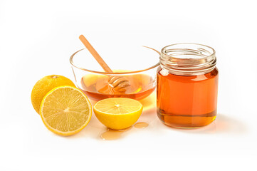 Close up Glass bowl of pure honey with honey bottle honey dipper and lime on white background.