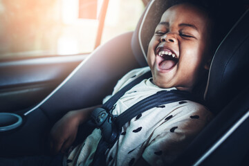 Happy African American kid in a car seat