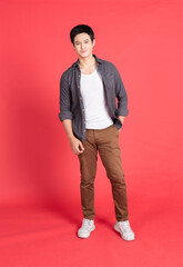 Portrait of young asian man in fashion casual dress stranding isolated on red background.