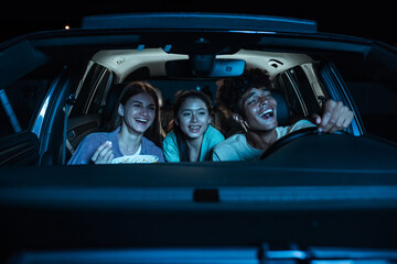 Portrait of three young friends looking emotional, laughing while sitting together in the car and...