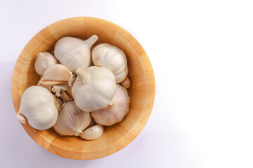 Garlic in a wooden bowl on a white background