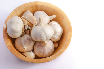 Garlic in a wooden bowl on a white background